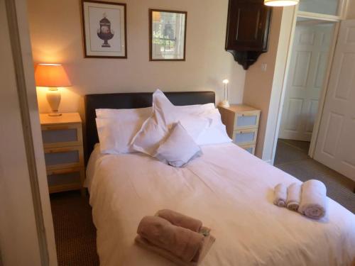 Un dormitorio con una cama blanca con toallas. en Central Georgian Garden Flat with Free Parking, en Bath