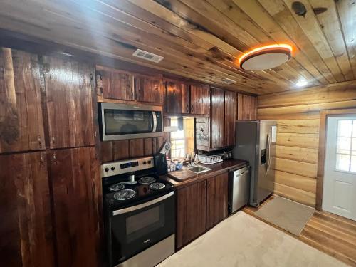 een keuken met houten kasten, een fornuis en een koelkast bij Jewel Branch Cabin in Erwin