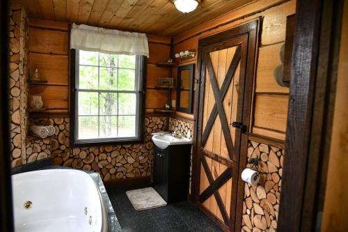uma casa de banho com uma porta de madeira, uma banheira e um lavatório. em Treehouse in Maine woods- The Grand Oak em North Lovell