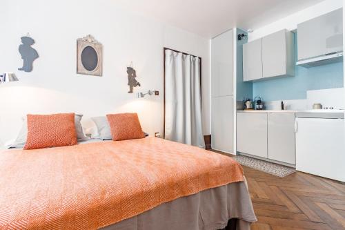 Cet appartement comprend une chambre dotée d'un lit avec des draps orange et une cuisine. dans l'établissement Studio François 1er, à Amboise
