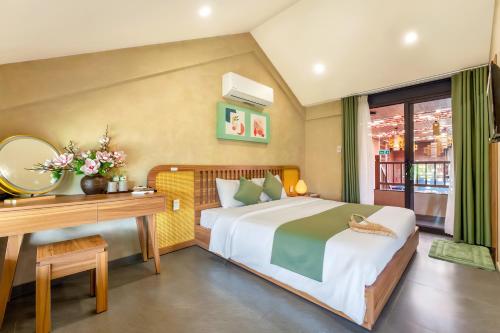 a bedroom with a bed and a desk and a mirror at The Linh Seaside Villa Hoi An in Hoi An