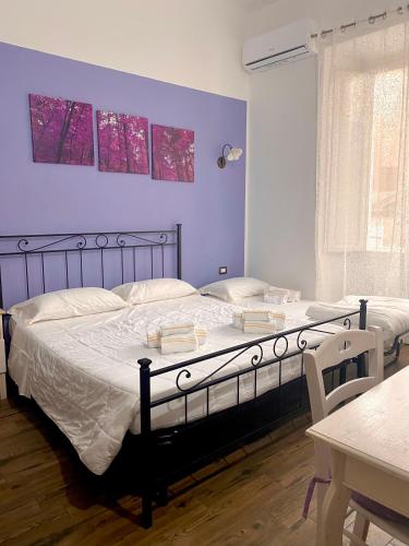 a bedroom with two beds and a purple wall at Dani's House - affittacamere nel cuore di Cagliari in Cagliari