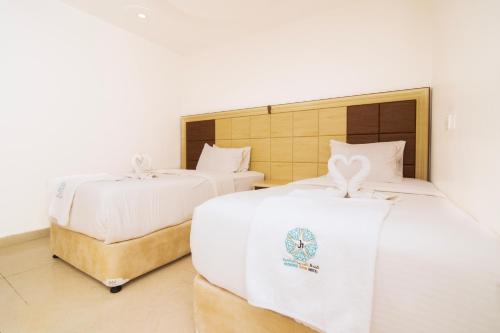 two beds with white sheets in a room at Diamond Star Hotel فندق النجمة الماسية in Seeb