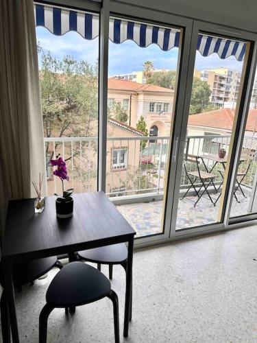 une table et une chaise devant une grande fenêtre dans l'établissement Orangers - Bord de mer - Studio cosy 4 personnes, à Cagnes-sur-Mer