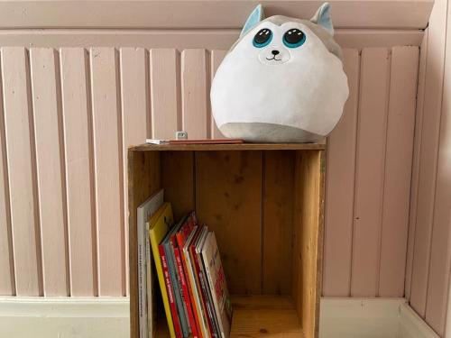 a stuffed cat is sitting on top of a book shelf at Mysigt hus för 2 familjer in Västervik