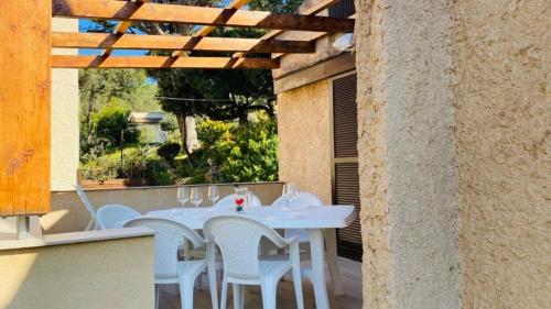 une table blanche et des chaises assises sur une terrasse dans l'établissement Maison Solane 1 Lumio, à Lumio