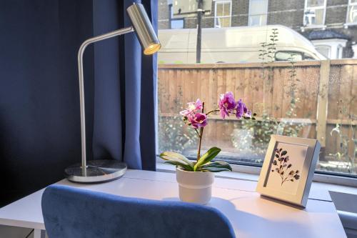 uma secretária com uma cadeira azul, uma fotografia e uma flor em The Finsbury Deluxe Apartments em Londres