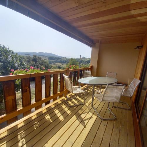 a wooden balcony with a table and chairs on it at Chambre d'Hôtes Côté Glycine in Juré