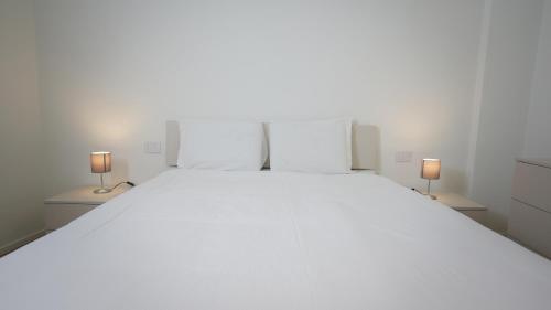 - une chambre avec un grand lit blanc et deux lampes dans l'établissement Palazzo Gilberto, à Padoue
