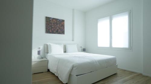 a white bedroom with a white bed and a window at Palazzo Gilberto in Padova
