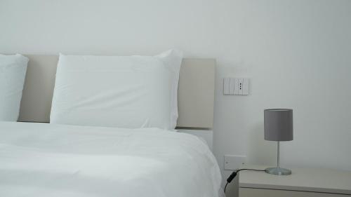 a white bed with white pillows and a lamp at Palazzo Gilberto in Padova