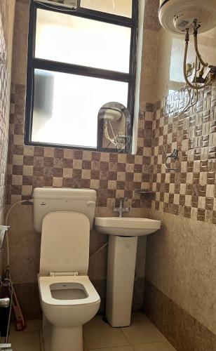 a bathroom with a toilet and a sink and a window at HOTEL COMFORT INN in Bhiwāni