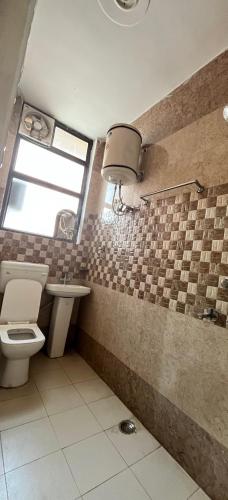 a bathroom with a toilet and a sink and a window at HOTEL COMFORT INN in Bhiwāni
