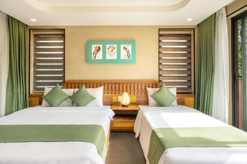 a bedroom with two beds and a couch at The Linh Seaside Villa Hoi An in Hoi An