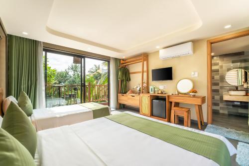 a hotel room with two beds and a television at The Linh Seaside Villa Hoi An in Hoi An