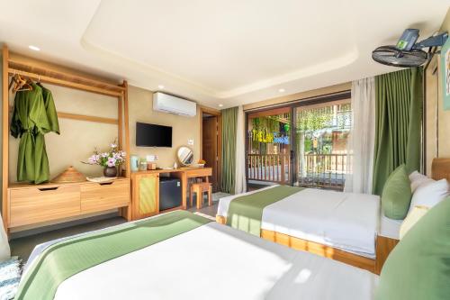 a hotel room with two beds and a television at The Linh Seaside Villa Hoi An in Hoi An