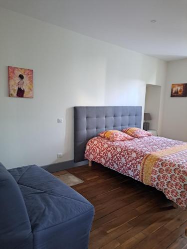 um quarto com uma cama e um sofá em Au P'tit Gueul'ton em Les Aix-dʼAngillon