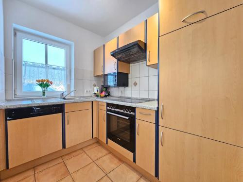 a kitchen with wooden cabinets and a window at Ferienhaus Baltrumkieker Links in Neßmersiel