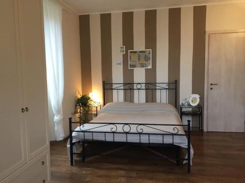 ein Schlafzimmer mit einem Bett und einer gestreiften Wand in der Unterkunft Charming & bright apartment Como lakefront in Argegno