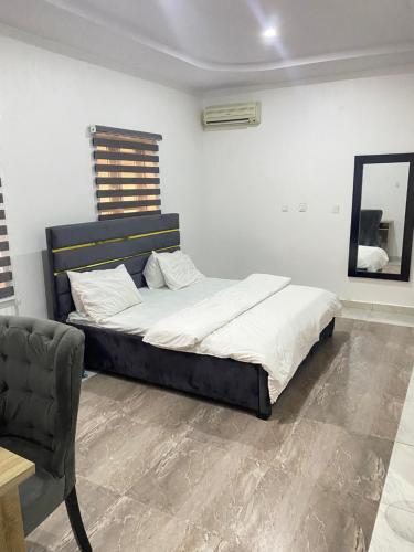 1 dormitorio con 1 cama grande y 1 silla en CHRIS SPORSHE en Abuja