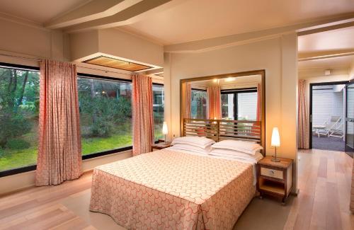 a bedroom with a large bed and large windows at Ethra Reserve Alborèa in Castellaneta Marina