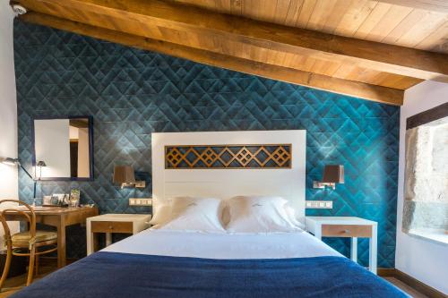 a bedroom with a blue accent wall and a bed at Pazo da Pena Manzaneda in Manzaneda