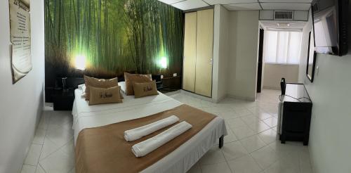 a bedroom with a large bed with two towels on it at Hotel Sulicam in Neiva