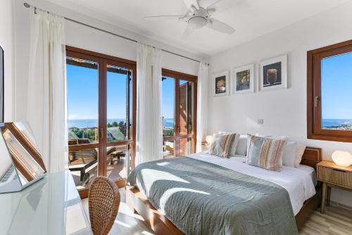 Biała sypialnia z łóżkiem i balkonem w obiekcie 2 bedroom Apartment Thalassa with sea and sunset views, Aphrodite Hills Resort w mieście Kuklia