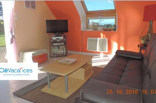uma sala de estar com um sofá e uma televisão em Maison 6 personnes vue mer em Plougrescant
