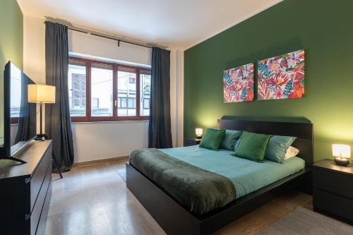 een groene slaapkamer met een bed en een televisie bij Home Principe Amedeo 184 in Bari