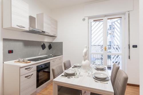 een witte keuken met een eettafel en een raam bij Home Principe Amedeo 184 in Bari