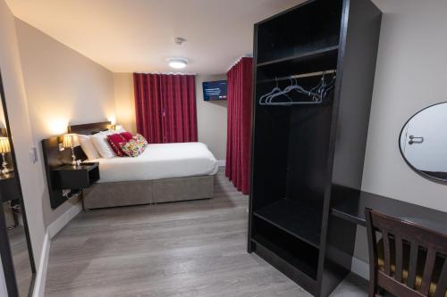 a small bedroom with a bed and red curtains at Behan's Horseshoe Bar & Restaurant in Listowel