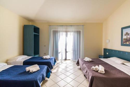 Habitación con 3 camas y toallas. en HOTIDAY Resort San Nicola, en San Nicola Arcella