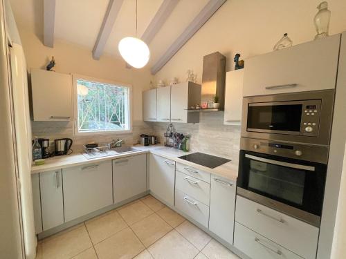 une cuisine avec des armoires blanches et un micro-ondes dans l'établissement Villa San Antonu, Santa Giulia, à Porto-Vecchio