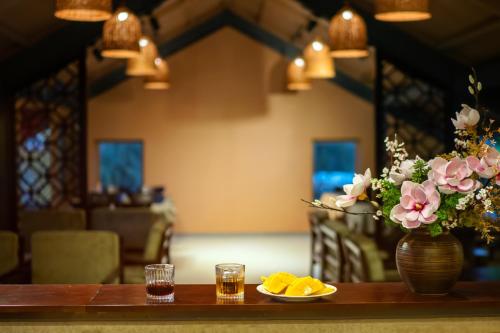 a table with a vase of flowers and a plate of fruit at The Linh Seaside Villa Hoi An in Hoi An