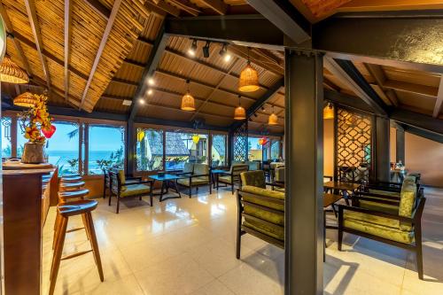 a restaurant with benches and tables and a view of the ocean at The Linh Seaside Villa Hoi An in Hoi An