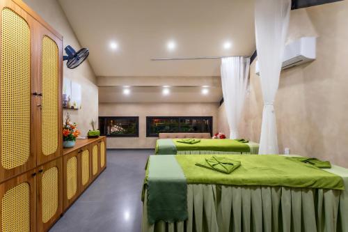 a room with two beds with green sheets at The Linh Seaside Villa Hoi An in Hoi An