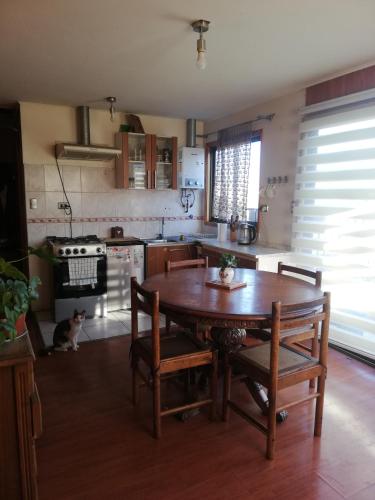 - une cuisine avec une table et des chaises en bois ainsi qu'un chat dans l'établissement Departamento 4 personas central, à Viña del Mar
