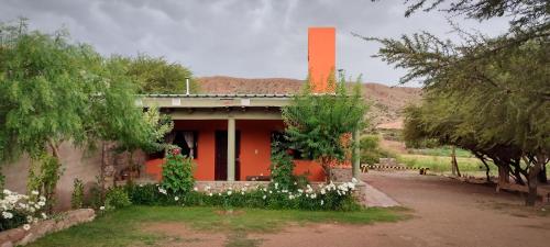a house with an orange chimney with flowers in front of it at Cabañas Kurmi in Humahuaca