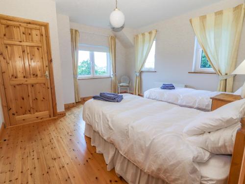 1 dormitorio con 2 camas y 2 ventanas en Cloughoge House en Kilrush