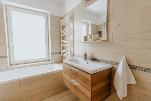La salle de bains est pourvue d'un lavabo, d'une baignoire et d'une fenêtre. dans l'établissement Lotus Apartman I, à Odorheiu Secuiesc