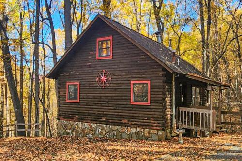 a log cabin with red windows in the woods at A Little Leeway in Ellijay