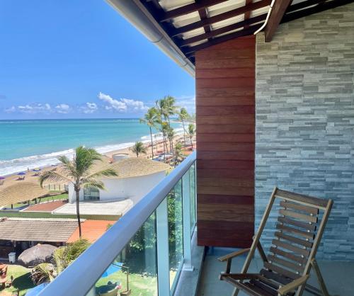 a chair on a balcony looking out at the beach at Pousada Maracabana Spa in Porto De Galinhas
