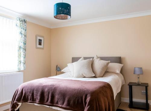 een slaapkamer met een bed met een paarse deken bij The Apartment at No.12 in Lochwinnoch