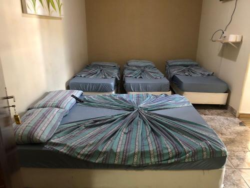 four beds in a room with an umbrella on them at Hotel Pousada Lega's in Aparecida