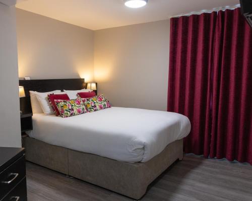 a bedroom with a large bed with red curtains at Behan's Horseshoe Bar & Restaurant in Listowel