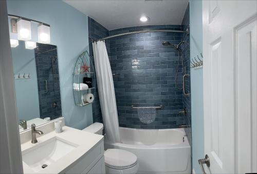 a bathroom with a white toilet and a tub and a sink at Private condo just steps to St Pete Beach in St Pete Beach