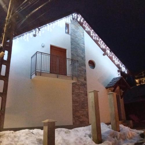 une maison avec un balcon dans la neige la nuit dans l'établissement Casa Mont Blanc Cavnic, à Cavnic