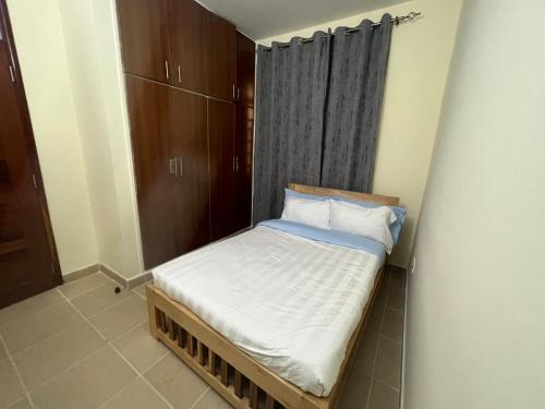 a small bed in a room with a curtain at Logic Stays 2 Bedroom Arusha City Centre in Arusha