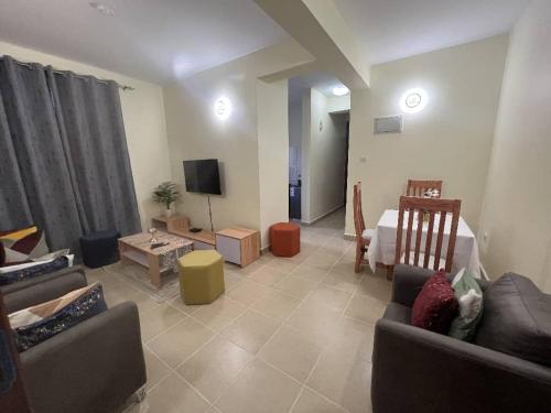 uma sala de estar com dois sofás e uma televisão em Elly's Cozy Apartment em Arusha